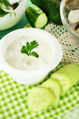 Cucumber yogurt in bowl, on color napkin, on wooden background