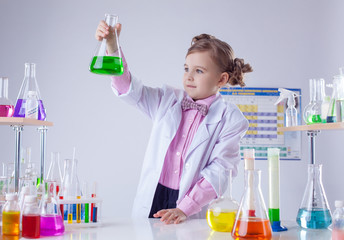 Cute chemist examines tubes with colorful reagent