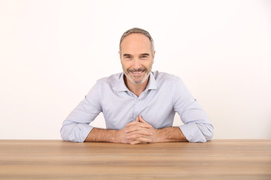 Attractive Senior Businessman Sitting At Table