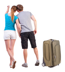 young couple traveling with suitcas and pointing at wal Back vie