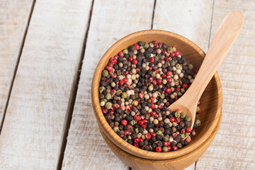 Mixed pepper in bowl  on wooden background