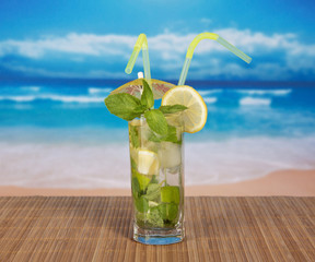 Mojito with cocktail straws against the sea