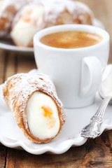 Cannolo siciliano pastry dessert with a cup of espresso coffee