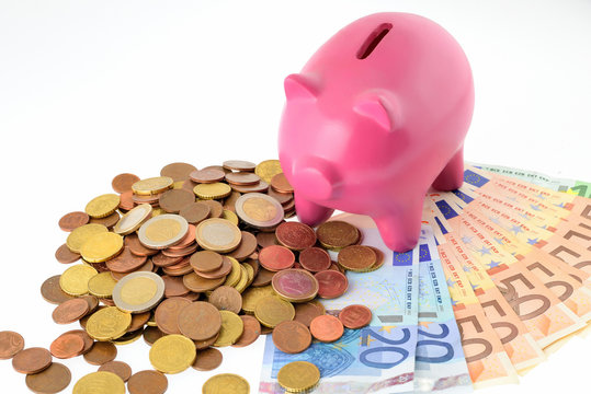 Maialino salvadanaio con soldi isolato su sfondo bianco