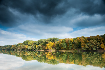 Fototapeta premium beautiful river and forest with dark sky in autumn