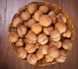 walnuts in a wicker basket on a wooden background