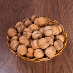 walnuts in a wicker basket on a wooden background