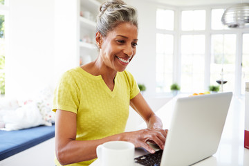 African American Woman Using Laptop In Kitchen At Home