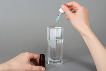 Drops in hands and a glass with water