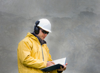 Engineer in safety suit writing a note in building log