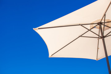 Part of white umbrella on background blue sky at the beach