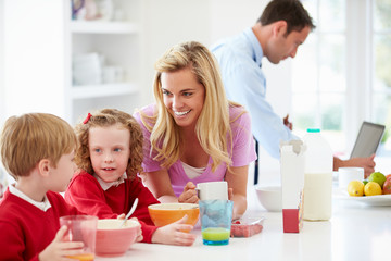 Family Having Breakfast In Kitchen Before School And Work
