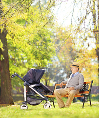 Grandfather on bench with his nephew in a stroller, in a park