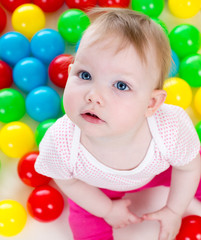 Fototapeta na wymiar Top view of baby girl playing with colorful balls