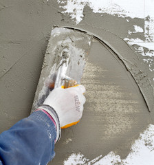 Mason spreading  mortar to styrofoam insulation with trowel