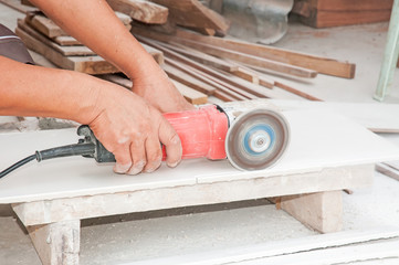 two worker hands cutting the stone tile by circular saw