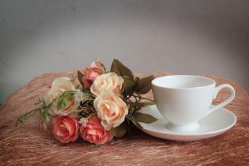 Cup of tea on wooden table with rose flowers
