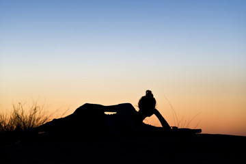 Silhouette de femme allongée, soleil couchant