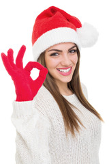 Cute young woman with Santa hat showing ok gesture