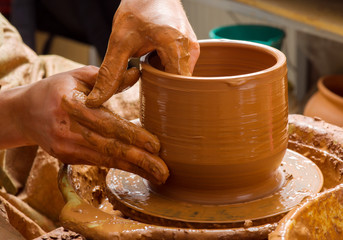 hands of a potter, creating an earthen jar on the circle