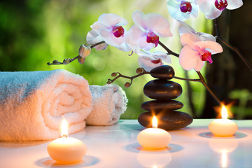 massage composition spa with candles, orchids, stones in garden