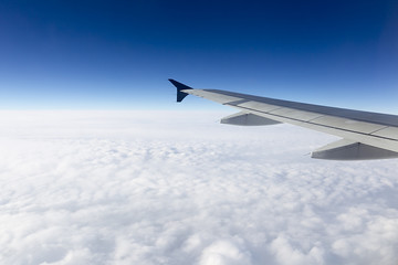 Fototapeta na wymiar Skrzydło samolotu latające nad chmurami na niebie