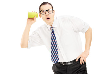 Young man listening through the wall with a cup