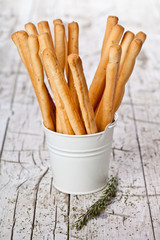 white bucket with bread sticks grissini and rosemary
