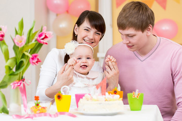 Obraz na płótnie Canvas young family celebrating first birthday of baby girl