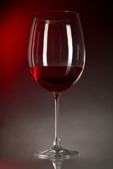 Glass of wine on table on bright red background