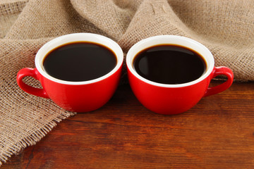 Red cups of strong coffee on table on sackcloth background