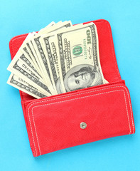 Purse with hundred dollar banknotes, on color background