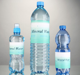 Different water bottles with label on grey background