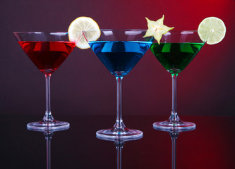 Alcoholic cocktails in martini glasses on dark red background