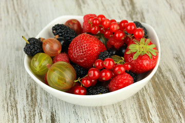 Ripe berries in bowl on table close-up