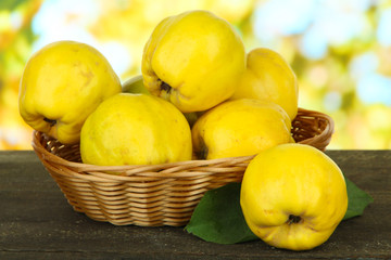 Sweet quinces in wicker basket on table on bright background