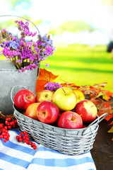 Juicy apples in basket on table on natural background
