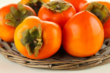 Ripe persimmons on wicker stand close up