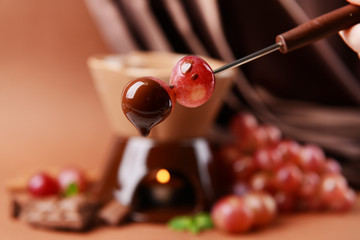 Chocolate fondue with fruits, on  brown background
