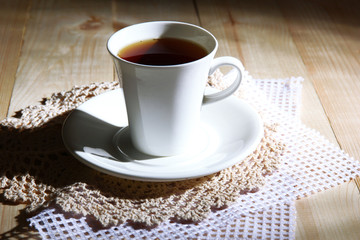 Cup of hot beverage on color wooden background, in dark