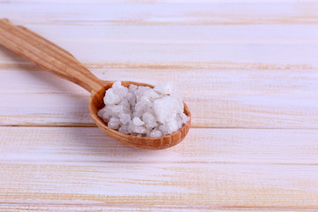 Wooden spoon with sea salt, on color wooden background