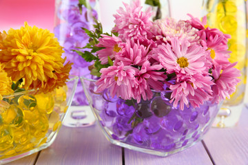 Obraz premium Beautiful flowers in vases with hydrogel on table close up