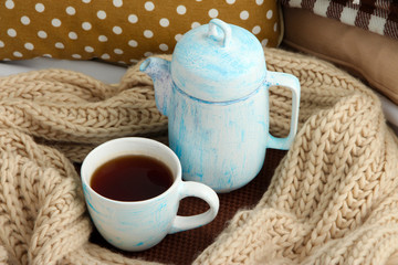 Cup and teapot with scarf on bed close up