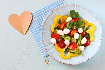 salad with mozzarella and fresh vegetables on wooden table backg