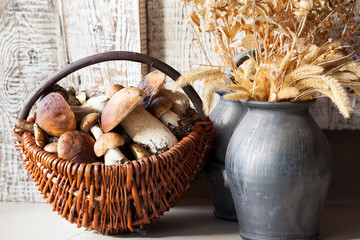 Fresh mushrooms in basket and vase, still life