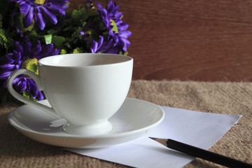 purple flower against the cup of herbal tea and paper note