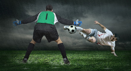 Two Football players in action under rain outdoors
