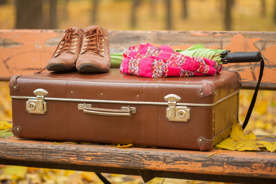 vintage suitcase, scarf, boots and umbrella on bench