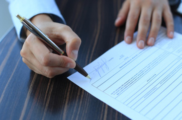 Businesswoman sitting at office desk signing a contract