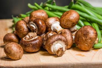 Mushrooms and green beans on a wooden board